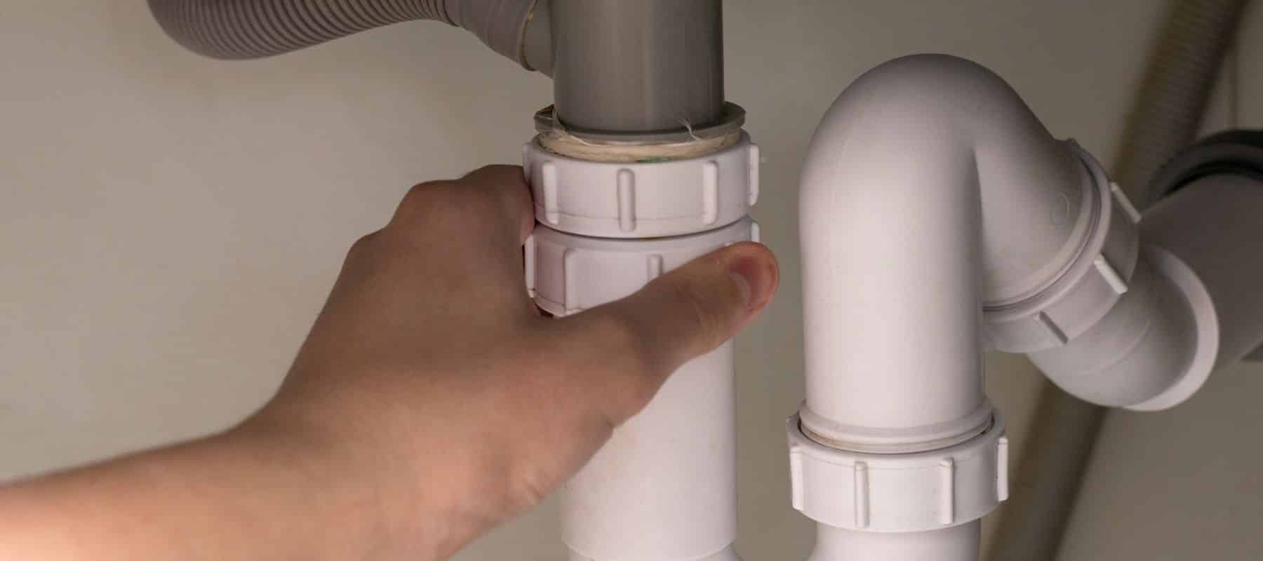 Hand tightening a plastic plumbing fitting under a sink
